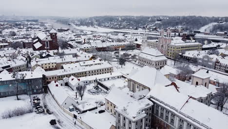 white snow-covered rooftops of kaunas old town during snowfall, aerial drone view
