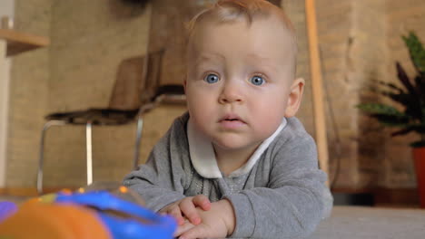 Baby-girl-in-gray-clothes-playing-on-the-carpet