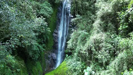 drone boom shot of narrow waterfall in forest