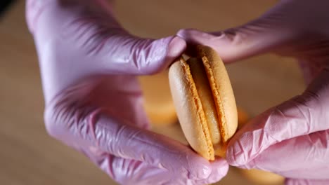 el chef de pastelería está llenando macarrones de limón con crema usando una bolsa de dulces.