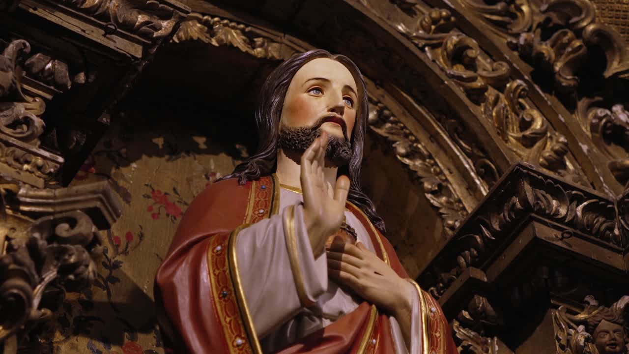 Statue of Jesus with a blessing gesture, set against intricate gold and floral carvings