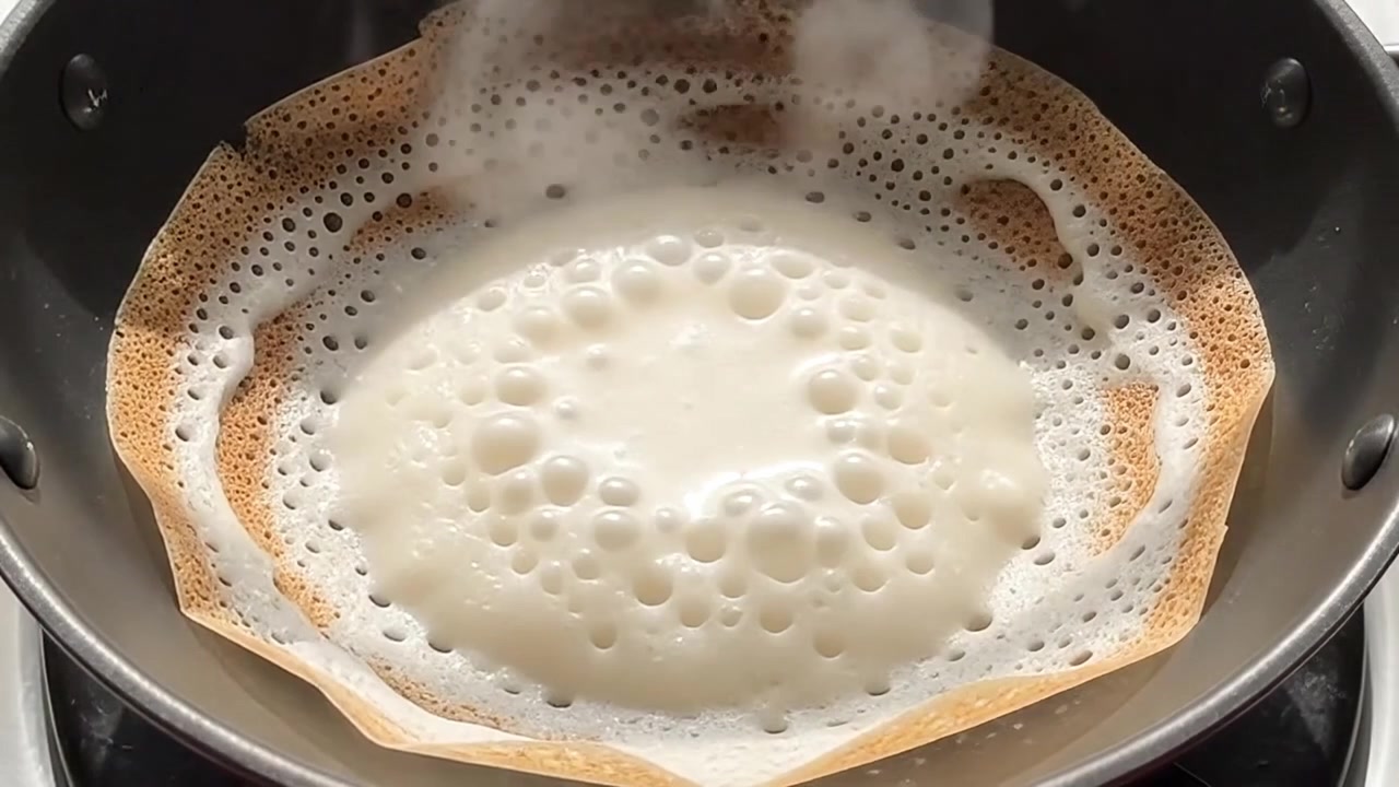 Versare e cucinare la pastella per Appam in una padella calda