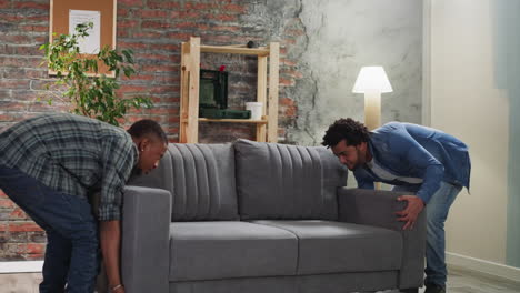 amigos afroamericanos llevan un sofá elegante en el apartamento
