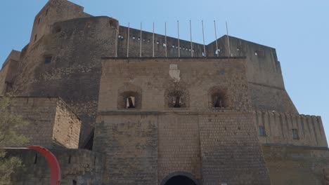 establishing shot of ovo castle, showing empty flag poles, a tunnel and multiple cannons, napoli