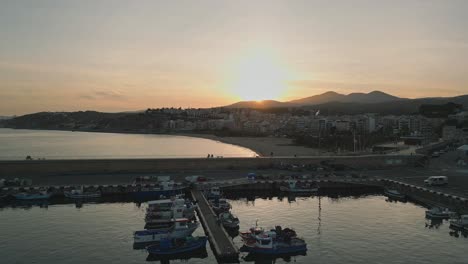 Vista-Aérea-Panorámica-Del-Amanecer-De-La-Playa-De-Arenys-De-Mar,-Barcelona,-Cataluña,-Horizonte-Dorado,-Paisaje-Cinematográfico-Del-Muelle,-Puerto-Marítimo-Y-Ciudad