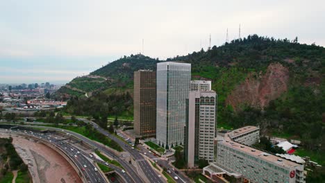 Volando-Hacia-Las-Torres-De-Santa-María-Por-El-Río-Mapocho-Y-El-Fondo-Del-Cerro-San-Cristobal,-Chile