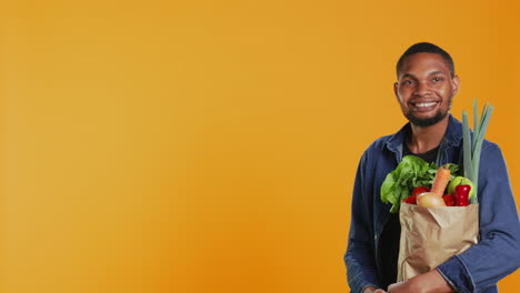 Portrait-of-african-american-guy-posing-with-a-paper-bag-full-of-groceries