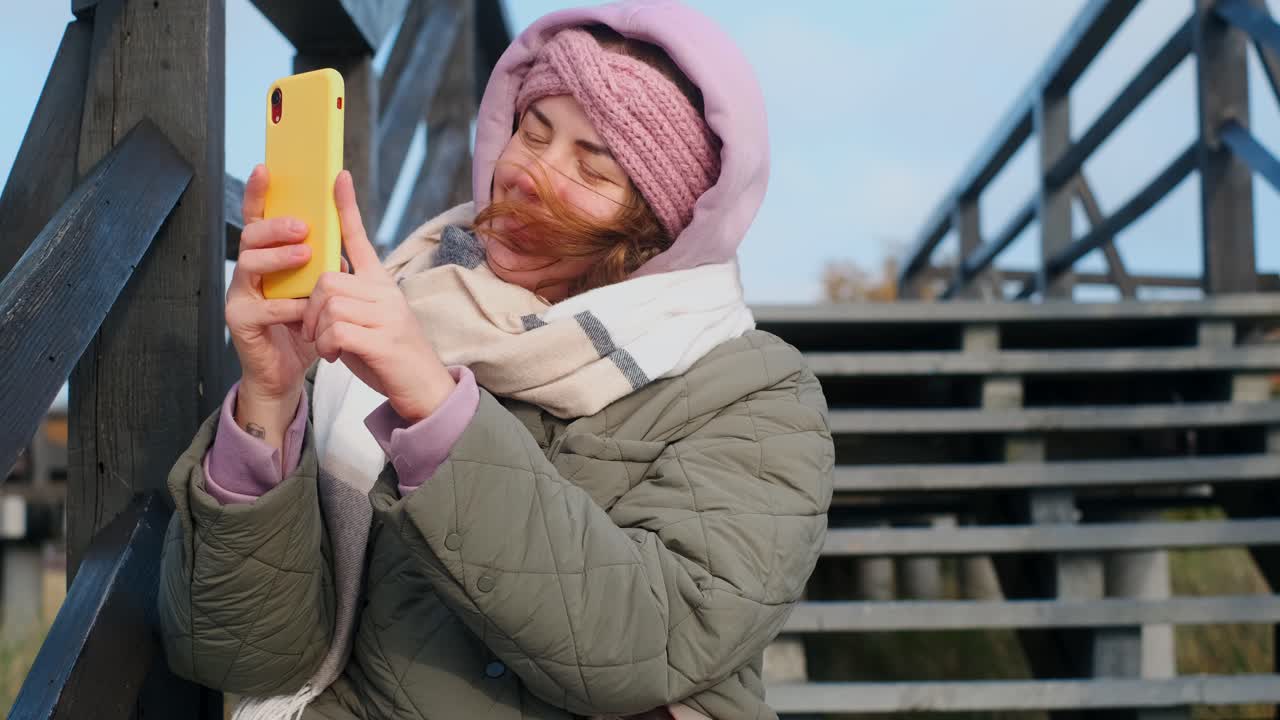 Woman taking a selfie on a wooden bridge in autumn