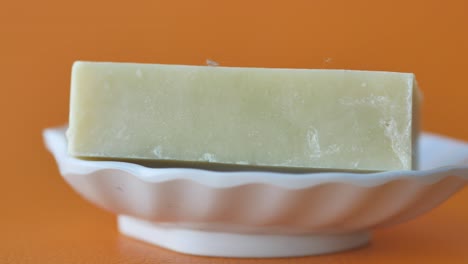 una barra verde claro de jabón en un plato blanco