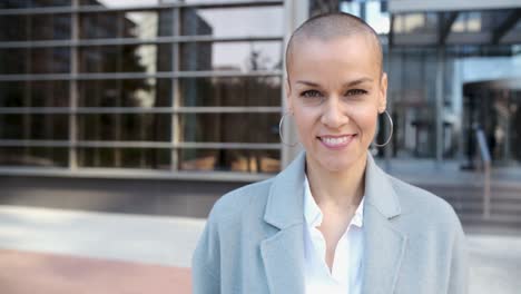 close-up view of a business woman looking at the camera while standing outside office building.