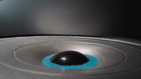 speaker with blue sand on diaphragm rotates and plays music