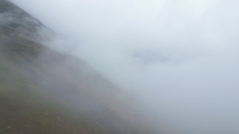 Drone-Shot-Flying-Against-Foggy-Mountain-Slope-Covered-in-Clouds