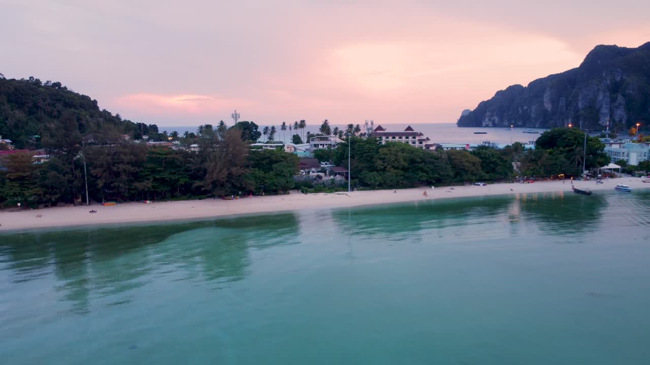 Panoramica all'indietro della spiaggia durante un bellissimo tramonto in una destinazione turistica tropicale di fama mondiale.