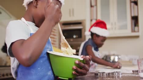 african american boy and girl wearing aprons baking together in the kitchen at home