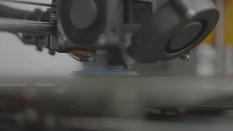 Macro-shot,-3D-printer-prints-object-from-blue-filament-in-the-white-room