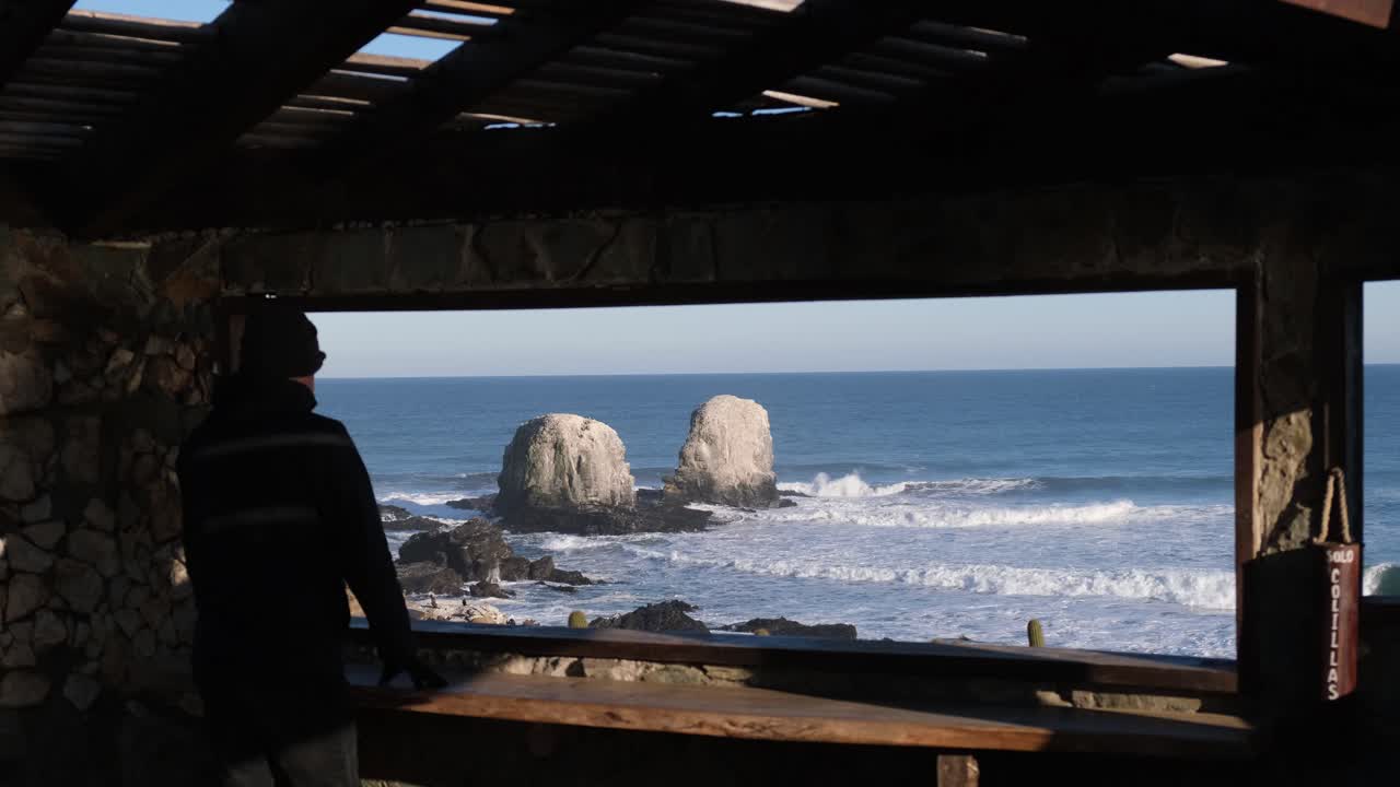 el hombre mira a través de un marco o una ventana hacia punta de lobos surf point chile sin mascarilla en la nueva normalidad de chile pichilemu