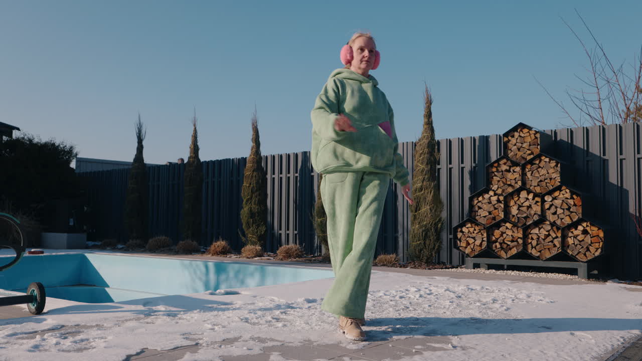 Donna che balla in un giardino invernale vicino alla piscina