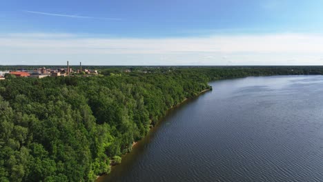 Panoramic-view-The-shore-of-the-lake-is-covered-with-trees,-and-behind-them-you-can-see-the-buildings-of-the-town