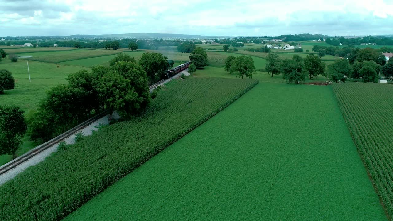 Treno a vapore che sbuffa attraverso i campi Amish visto da drone
