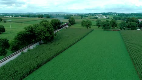 steam train puffing along amish farmlands as seen by drone
