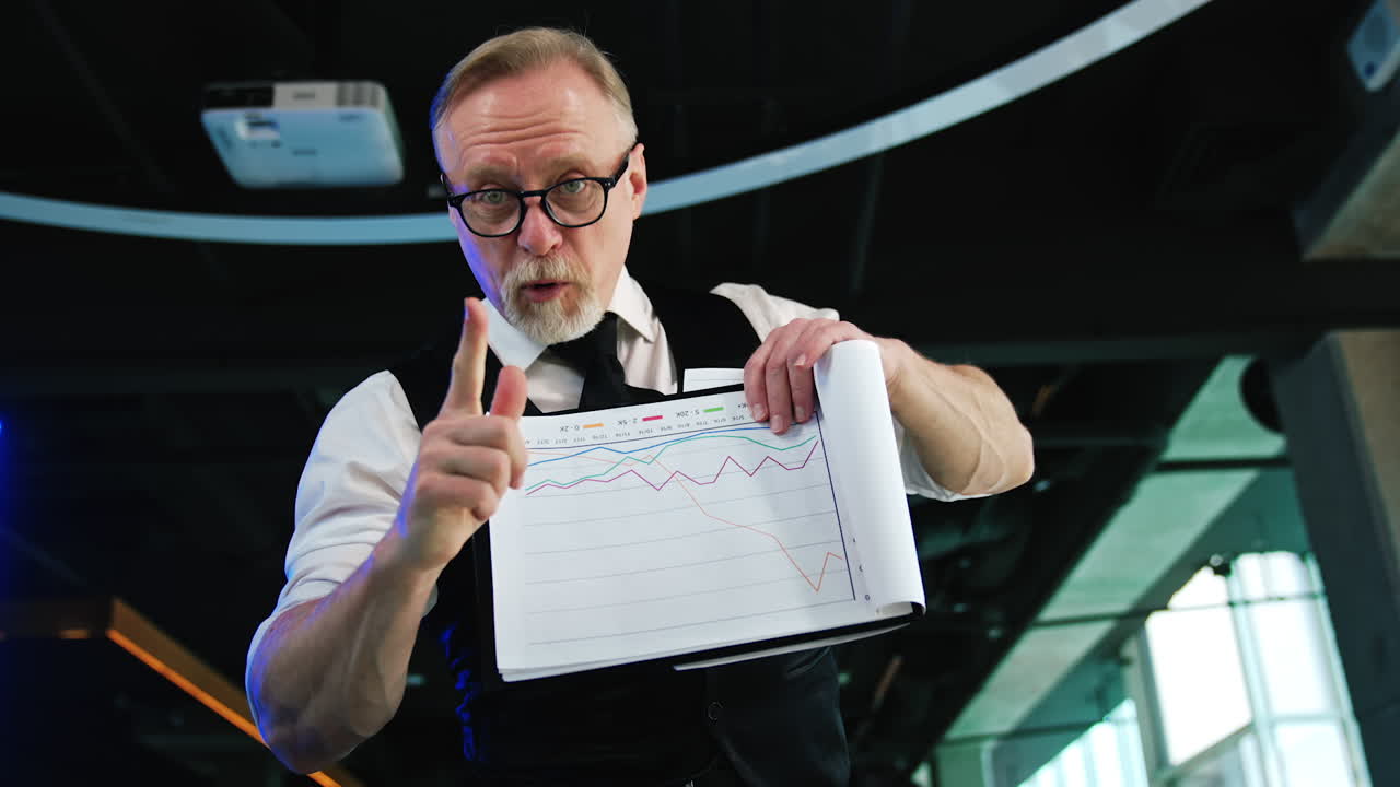 Active energetic businessman displaying papers with charts. Positive man working in the office. Low angle view.