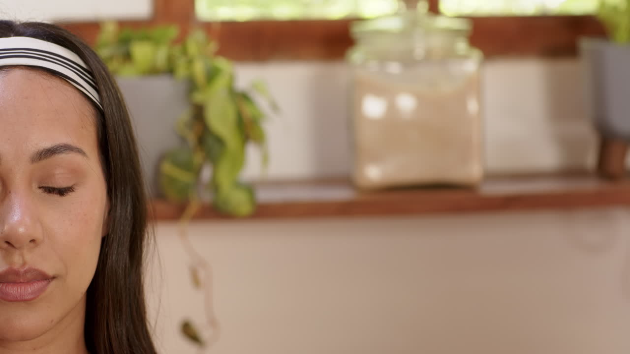 Woman with headband relaxing at home, surrounded by plants and natural light, copy space