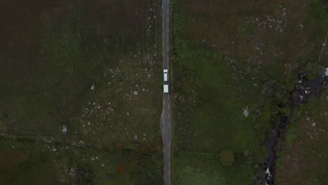 Aerial-birds-eye-overhead-top-down-view-of-off-road-car-with-trailer-driving-on-narrow-road-in-countryside.-Ireland