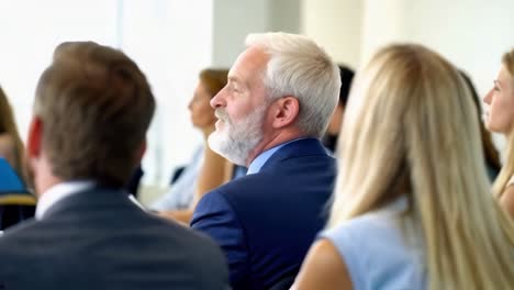 a close-up scene of a group of professionals attentively listening at a conference or seminar.