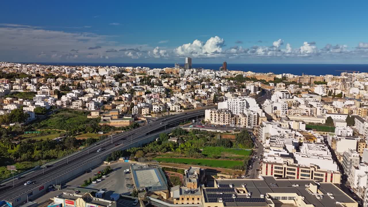 Aerial timelapse from Msida, Malta, on a sunny winter day with moving cars and clouds over the bustling cityscape of Kappara, San Ġwann, St Julian's and Swieqi areas
