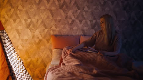 careful mommy with book adjusts blanket child rolls over