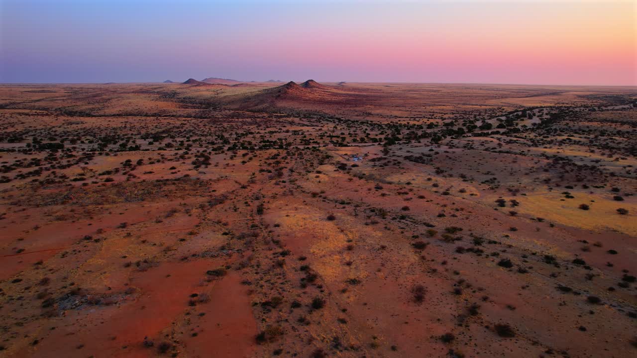 Colorful sunset aerial view of scattered shrubs and rolling desert hills near Spitzkoppe, Namibia