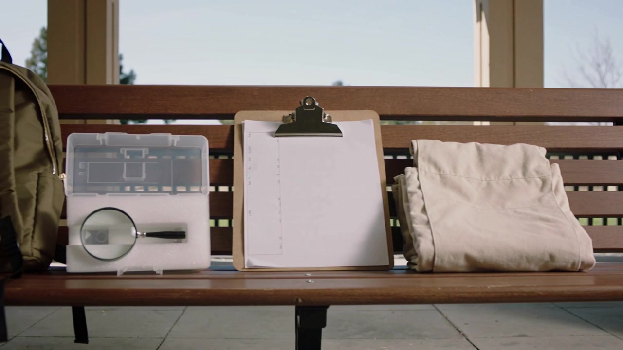 Arriving from left objects settling on wooden bench under shelter pack, lens, clipboard for survey