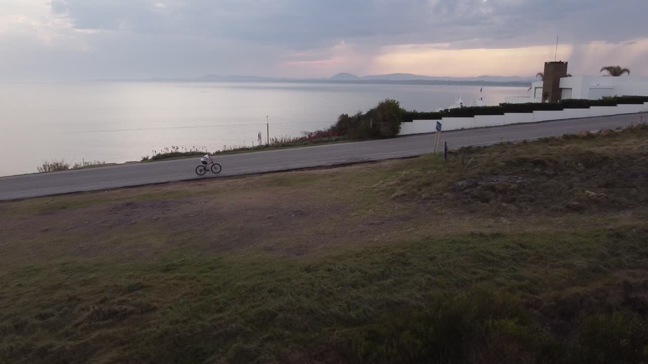ciclista aislado pedaleando a lo largo de la carretera frente al mar en punta ballena en uruguay