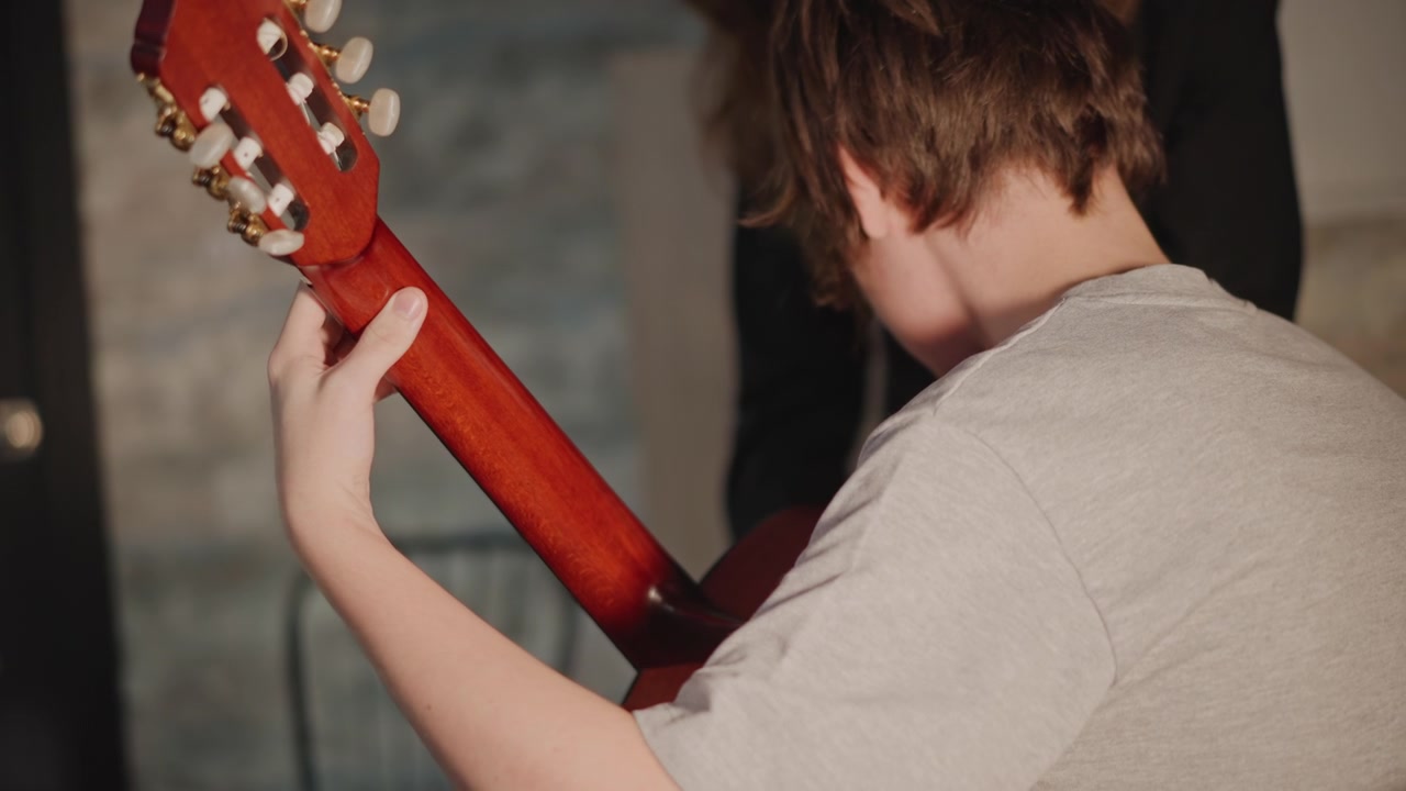 Focused young musician carefully practicing guitar skills silently and effectively. Committed adolescent student is quietly rehearsing and sharpening their guitar playing abilities