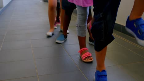 Untere-Gruppe-Von-Schulkindern,-Die-In-Einer-Reihe-Auf-Dem-Flur-Der-Schule-Marschieren,-4k