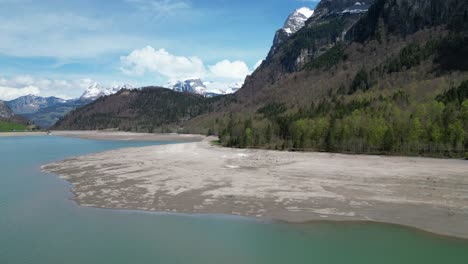 aerial forward view of shoreline of an alpine lake in a fantastic mountain landscape