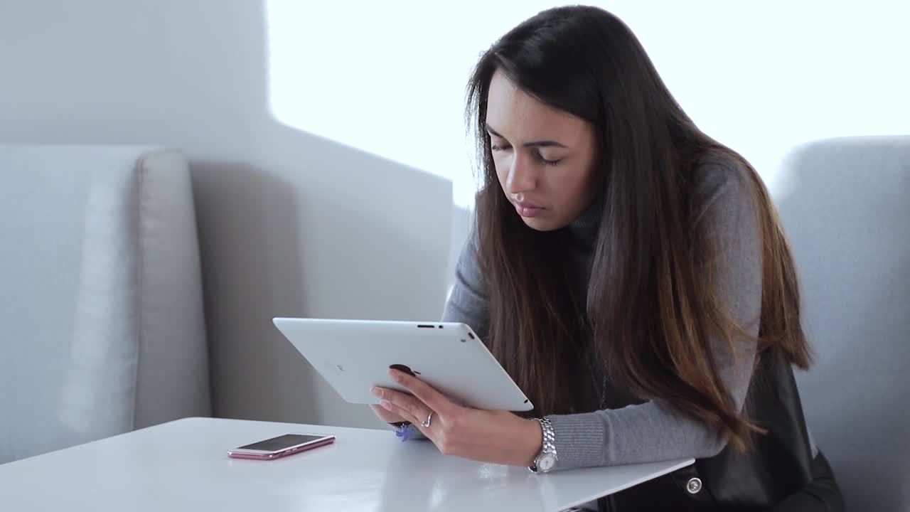 una hermosa chica sentada en la mesa de la oficina y usando su ipad.