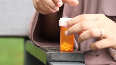 woman opening a bottle of pills outdoors