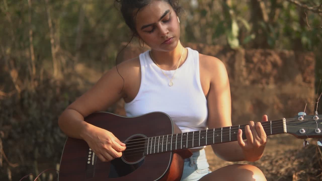 guitarra acústica tocada por una joven música hispana al aire libre, cámara lenta