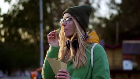 chica rubia comiendo papas fritas al aire libre en la calle de invierno bañada en ketchup