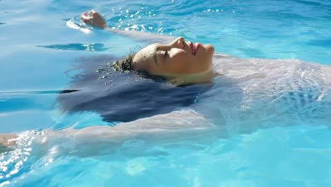 side view of young mixed-race woman floating in swimming pool on a sunny day 4k