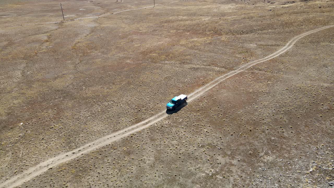 camión siguiendo un camino de tierra en un desierto - vista aérea