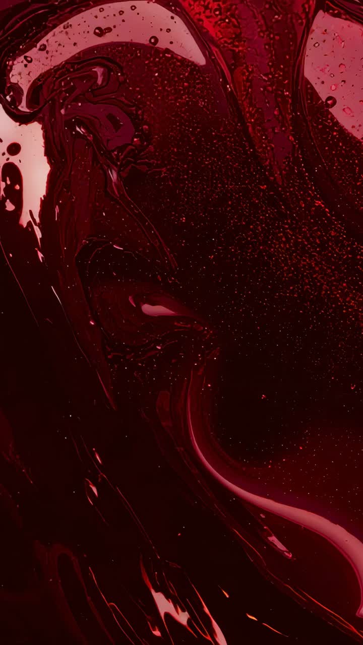 Vertical video: Shifting glossy red liquid surface rippling after light shift in studio, bubbles