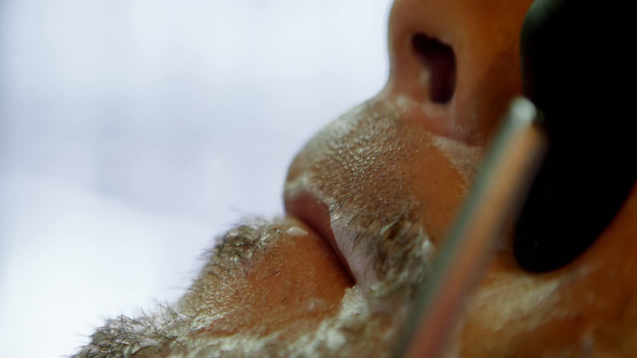 barbero varón afeitando la barba de un cliente en una barbería 4k