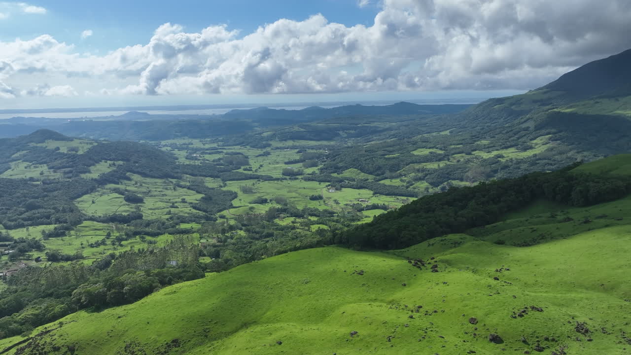 Splendida ripresa aerea 4K con drone che avanza e ruota verso destra per rivelare lussureggianti colline ondulate e una vasta valle verde sotto un cielo blu intenso nel sud del Brasile. Paesaggio rurale idilliaco