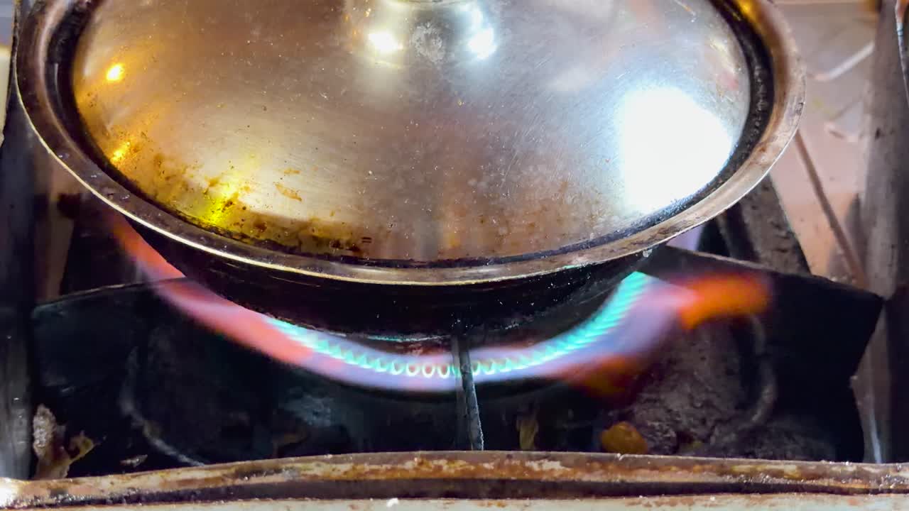 Un primo piano fisso di un fornello a gas che scalda una pentola di metallo in Thailandia.
