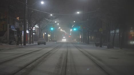 glowing headlights of oncoming car driving on a snow covered road in winter