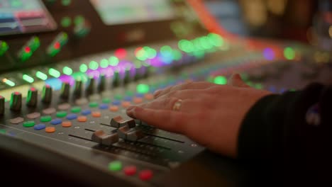 sound engineer hand controlling audio on mixer console at live music concert