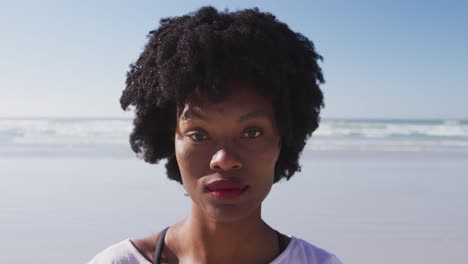 Mujer-Afroamericana-Mirando-La-Cámara-Y-Sonriendo-En-La-Playa-Y-El-Fondo-Del-Cielo-Azul