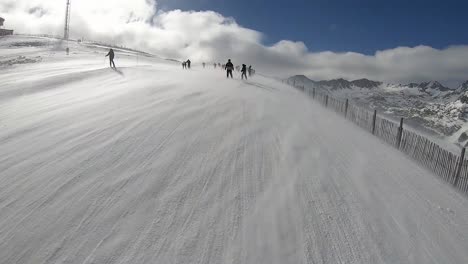 skiers try to advance against the strong wind in a ski resort in the alps, the snow is lifted from the ground by the wind